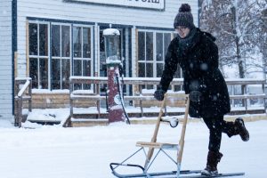person on a kicksled sledding past a store on village street